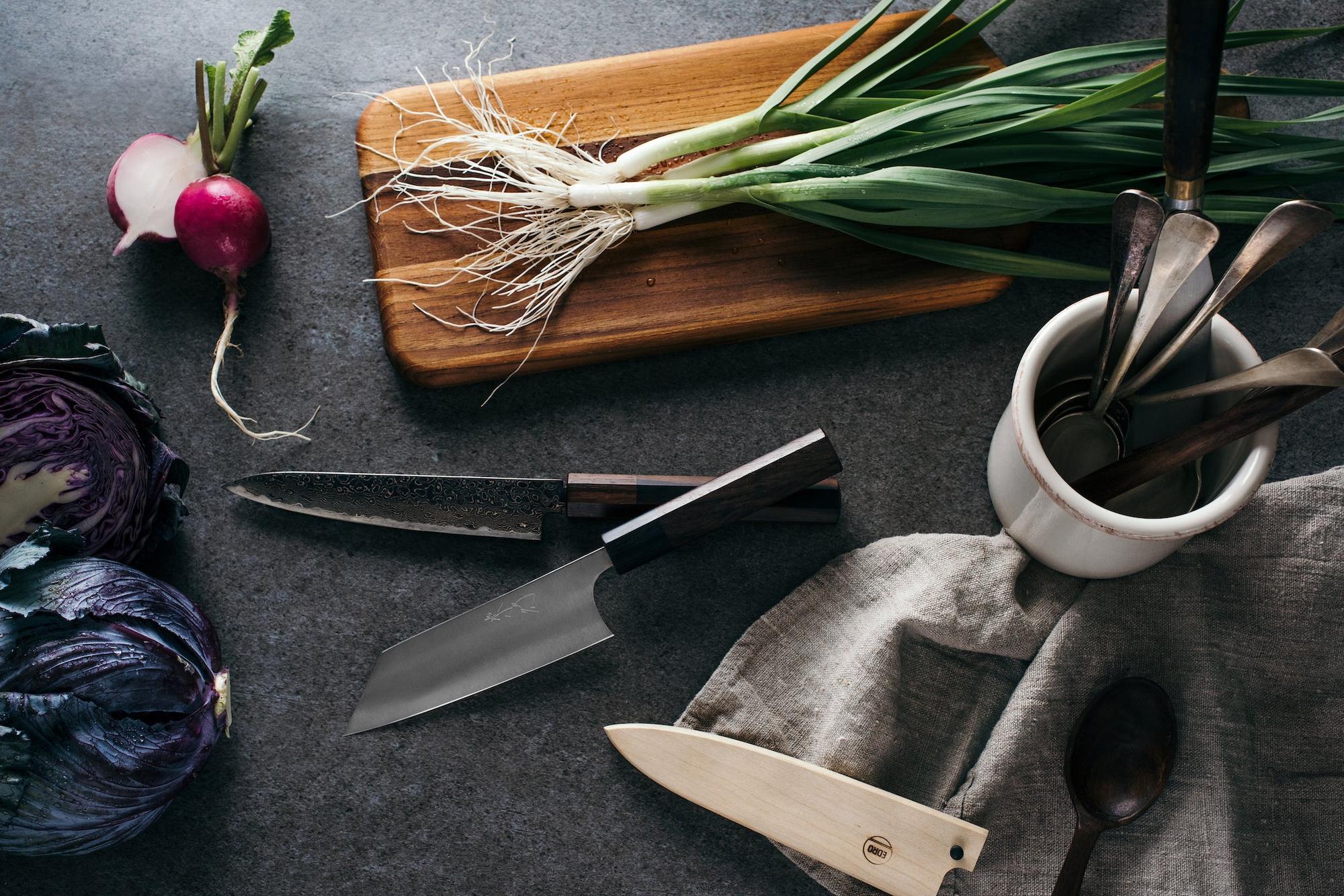 Japanese kitchen prep station featuring a hand-forged Petty knife, a ceramic silver spoons and vegetables.